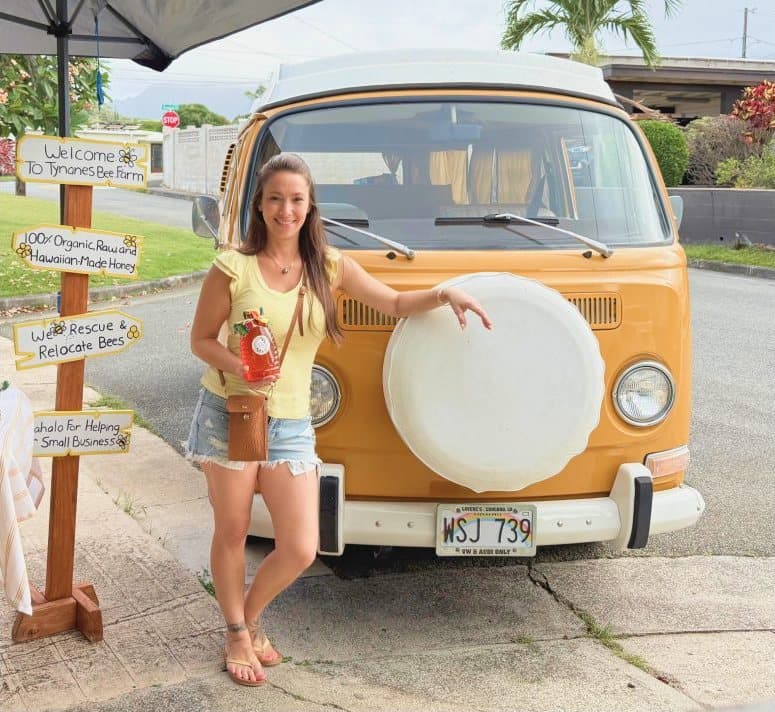Kristal Tynanes beside the Tynanes Bee Farms market stand and a vintage orange VW bus